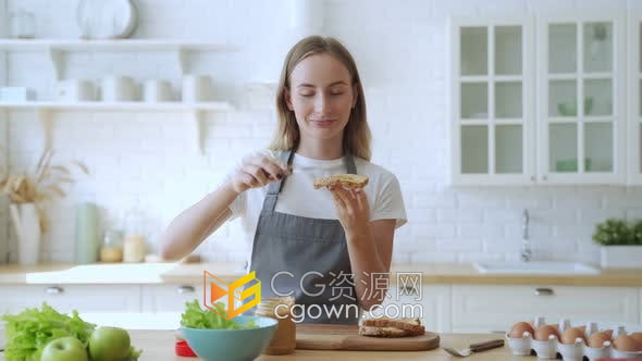 实拍素材-厨房里快乐微笑的女人准备花生酱三明治健康营养饮食宣传素材